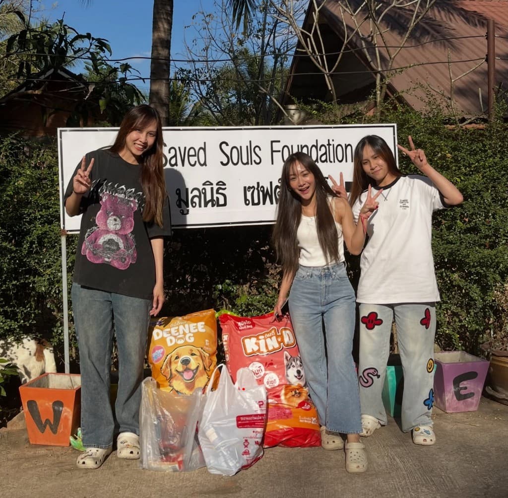 Saved Souls Foundation team members beside the sanctuary sign with bags of donated pet food